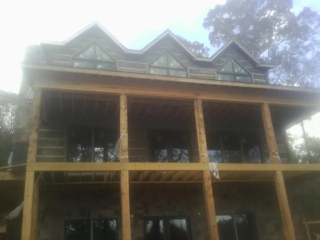 Dormers and porch framing on a large log home under construction — Roof Coating work by our crew in Maplewood