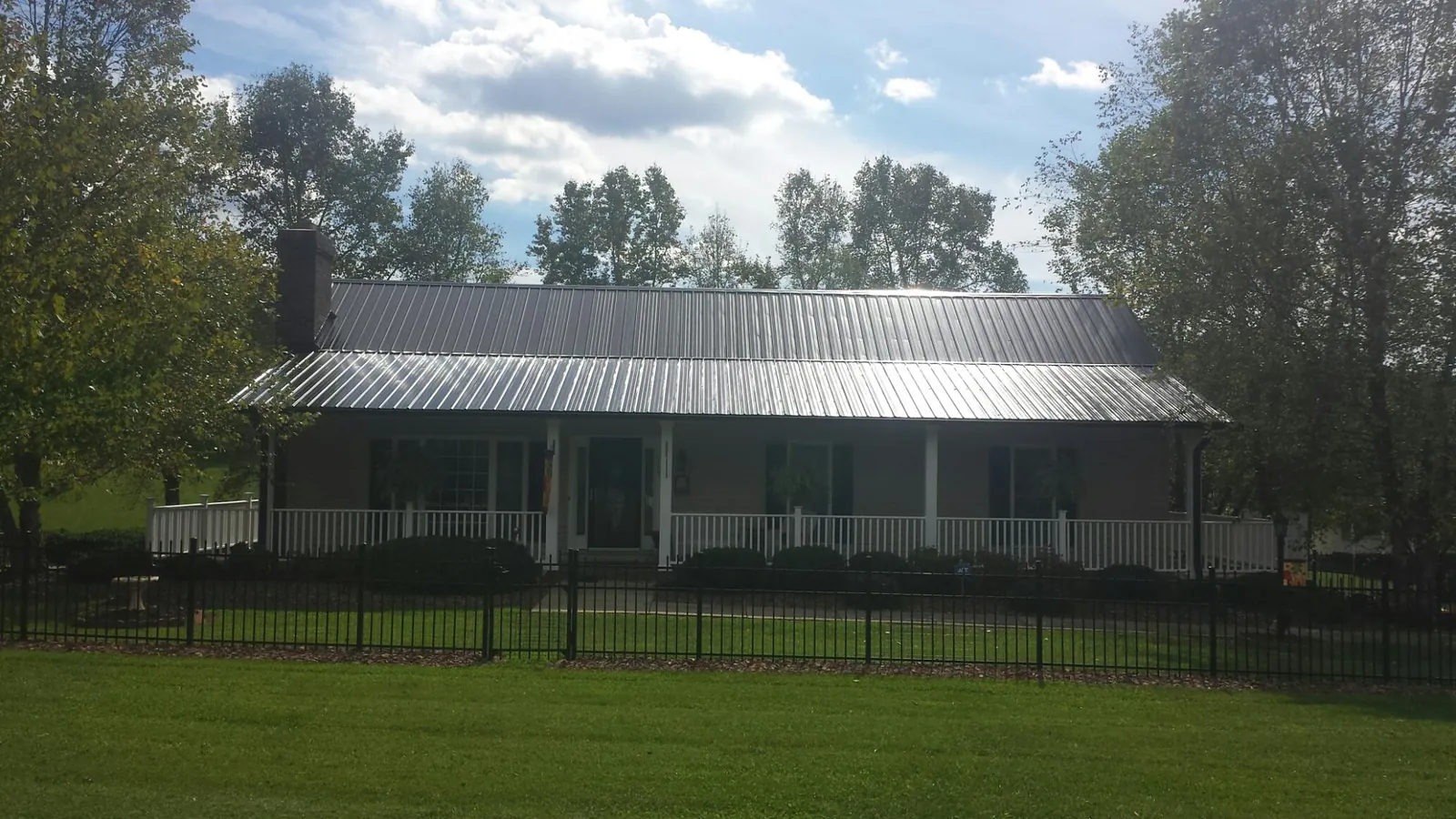 Gray metal roof on a brick ranch with a full width front porch — Gutter Guard Installation work by our crew in Maplewood