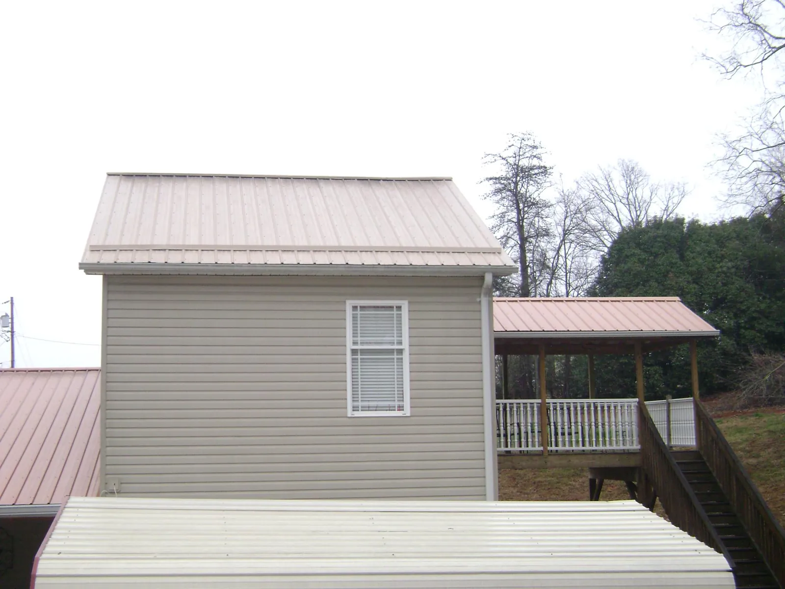 Tan metal roofs on a two story addition and attached porch, from a Roof Replacement job in Maplewood