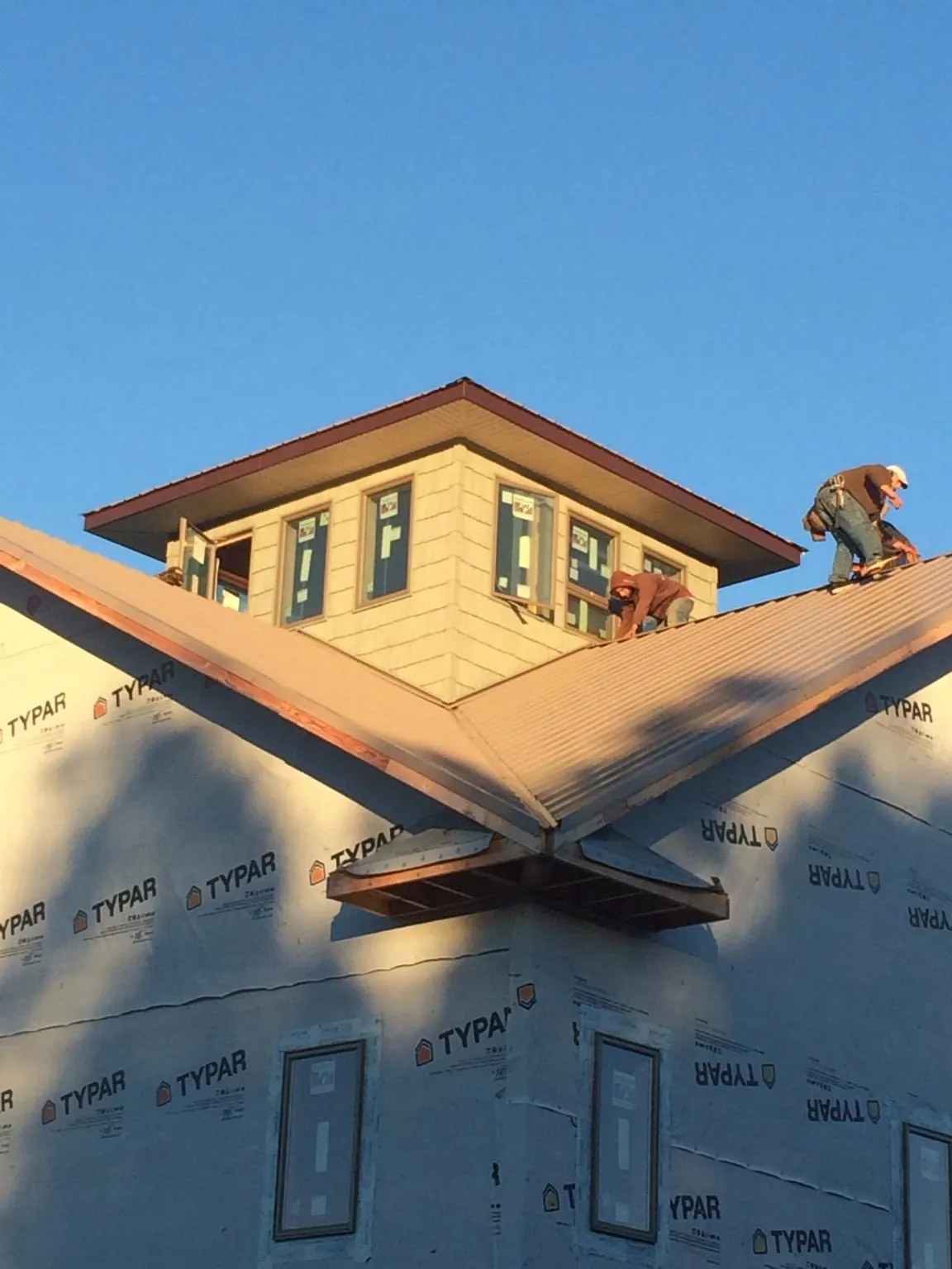 Roofers working around a rooftop cupola on a new metal roof at sunset — Roof Waterproofing in Maplewood by Roofing Brothers